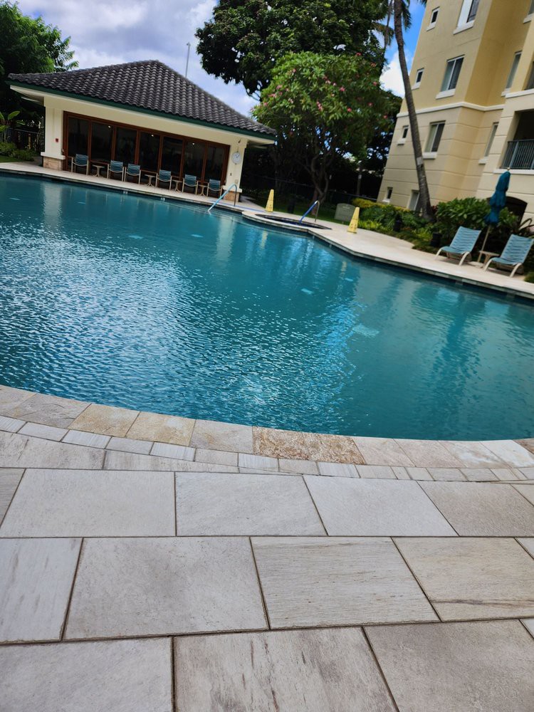 A tranquil outdoor pool surrounded by lounge chairs and greenery.