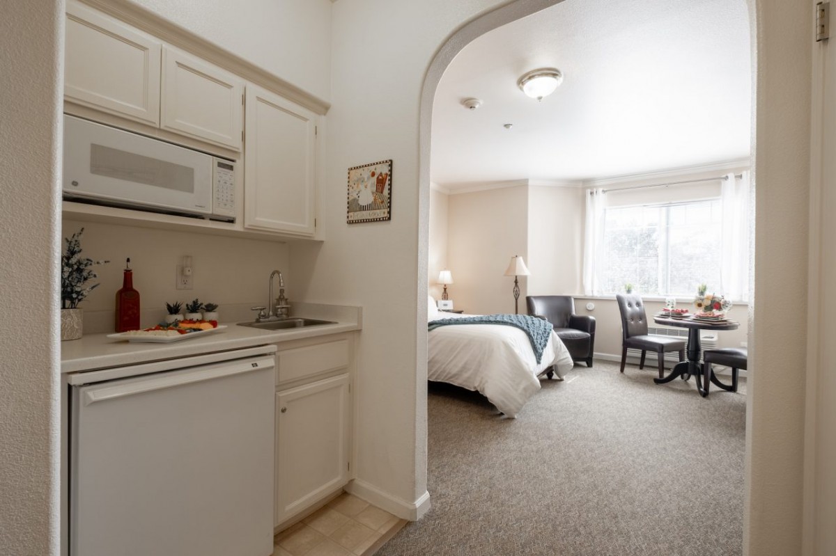 A cozy hotel room featuring a kitchenette and a comfortable sleeping area with a small dining setup.