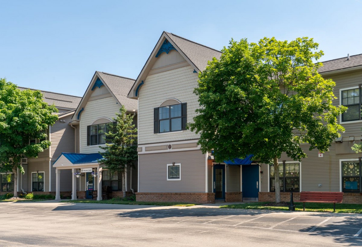 A commercial building with a tree in front, captured on a sunny day.