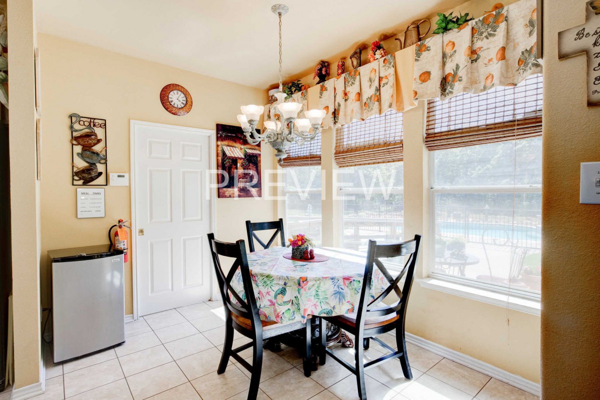 A cozy dining area with a table set for four, enhanced by natural light streaming through large windows and adorned with decorative elements.