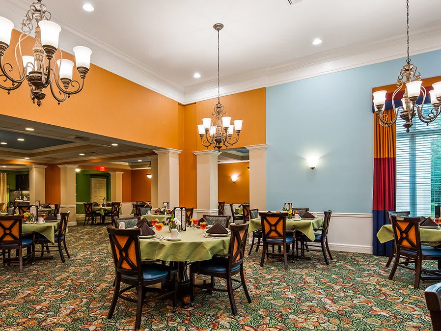A colorful dining room with elegantly set tables and chandeliers.
