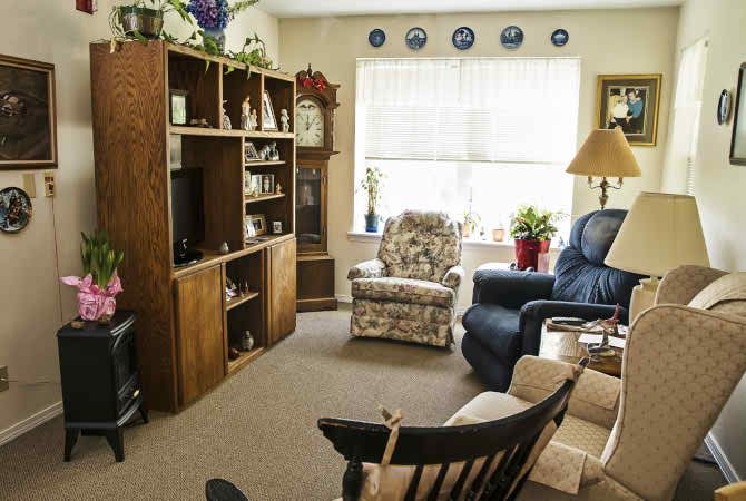 A cozy living room with armchairs, a bookshelf, and a television.
