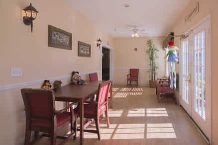 A sunlit dining area with red chairs and simple decor.
