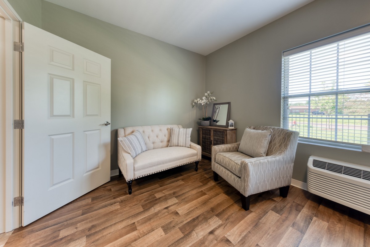 Cozy living room with a loveseat and an armchair on gleaming hardwood floors.