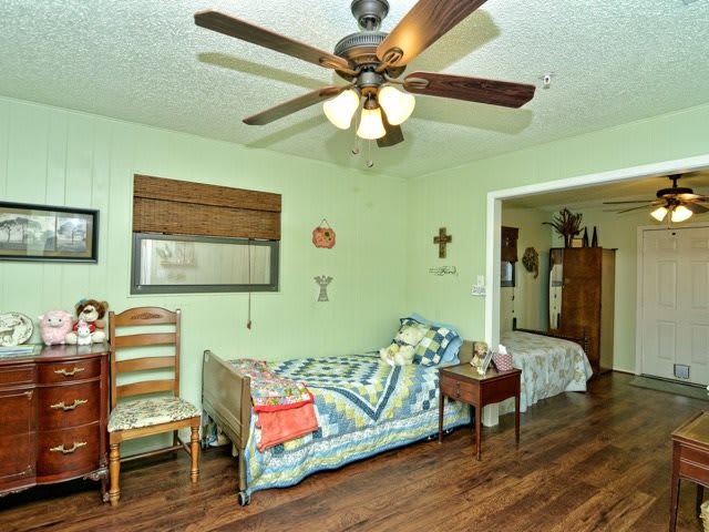 A cozy living room with a ceiling fan, sofa, and wooden flooring.