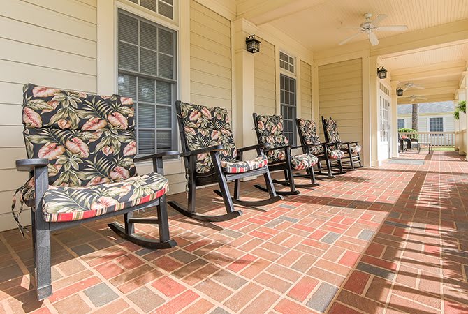 A cozy porch with rocking chairs and a brick floor.