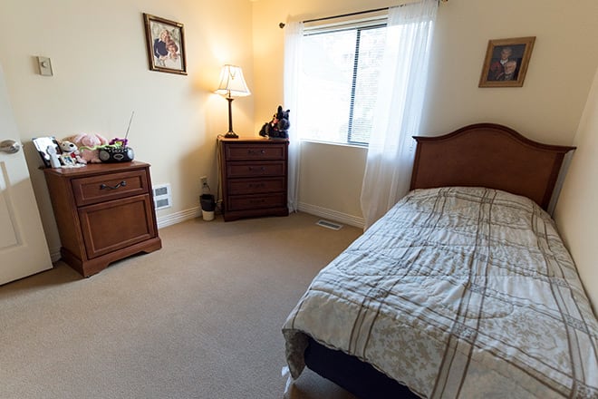 A tidy bedroom with a single bed, dresser, and a window letting in natural light.