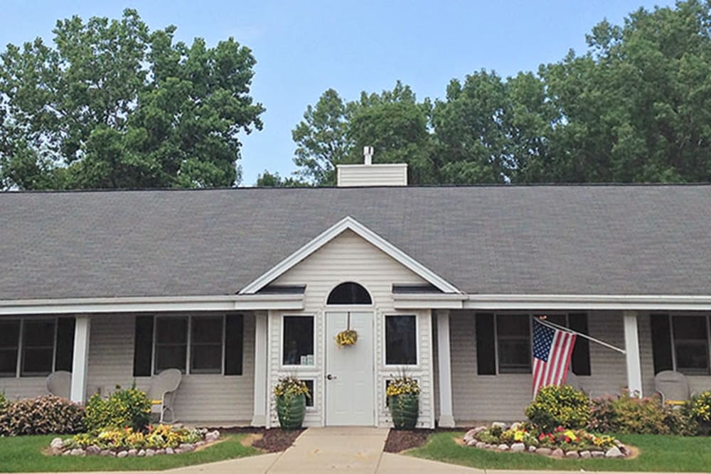 A charming single-story house with a well-maintained front yard featuring flowers and an American flag.