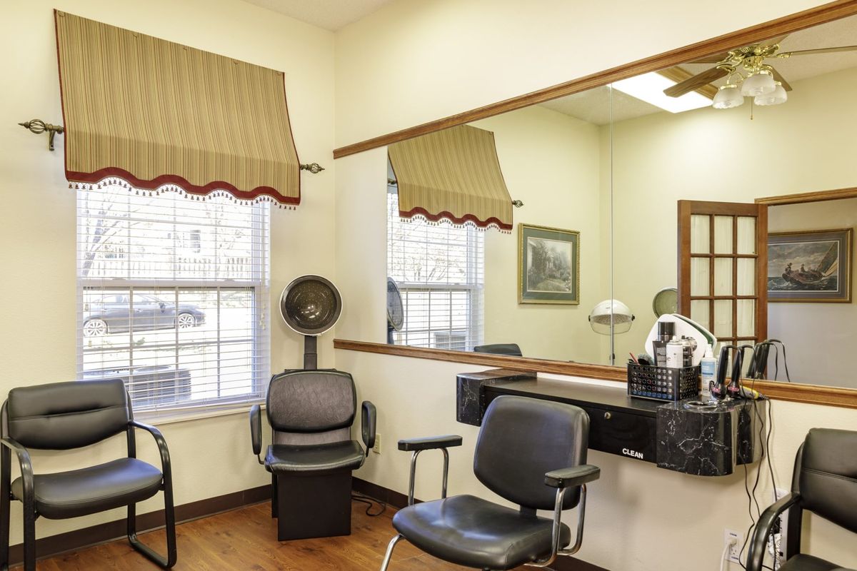A cozy hair salon interior with chairs, a mirror, and salon equipment.