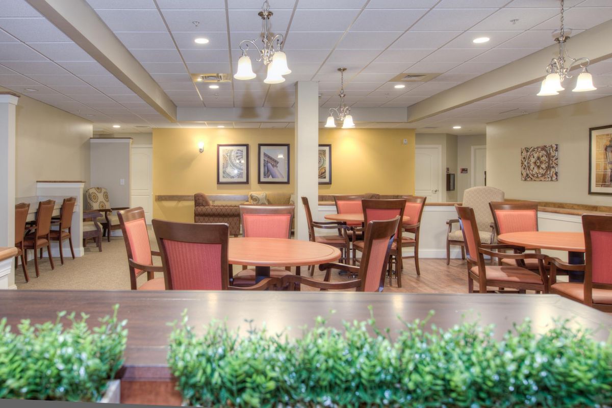 A cozy dining area with tables and chairs arranged neatly under warm lighting.