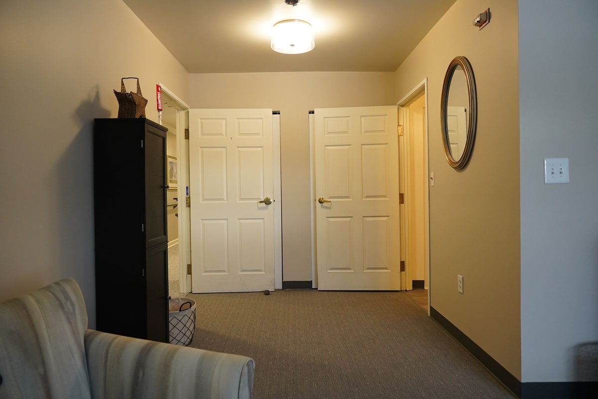 A cozy hallway with multiple doors, a mirror on the wall, and soft lighting.