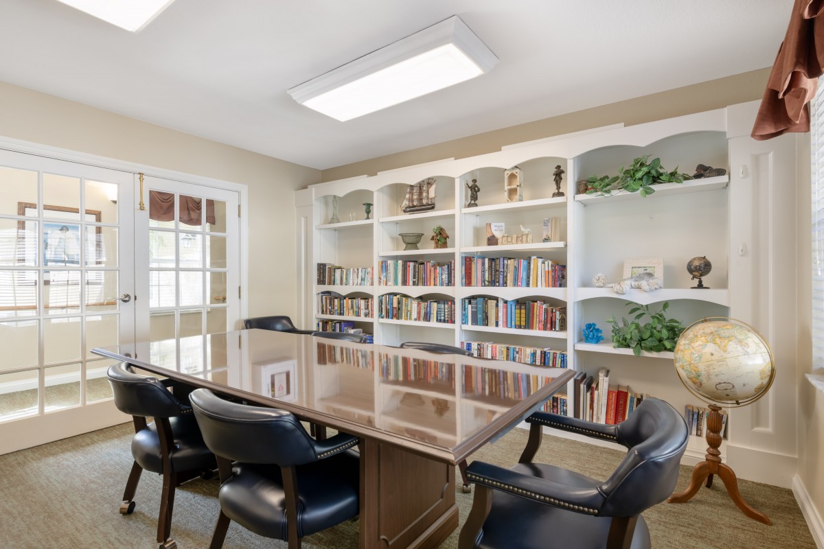 A well-organized conference room with a large table, chairs, and bookshelves filled with books.