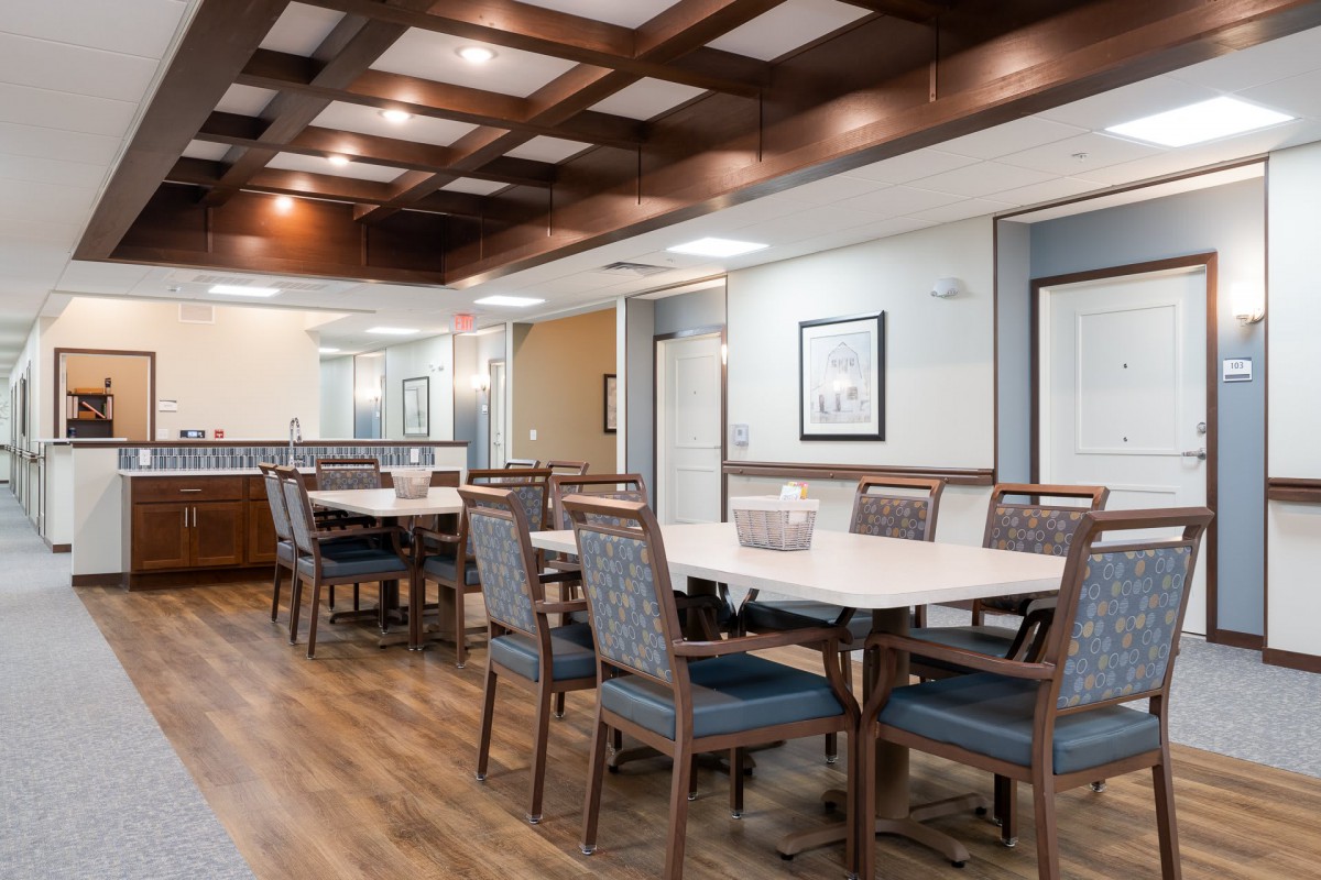A modern dining area featuring neatly arranged tables and chairs, with wood flooring and ceiling lights.