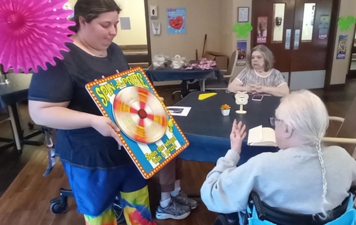 A group of people participating in an indoor activity involving a spinning wheel game.