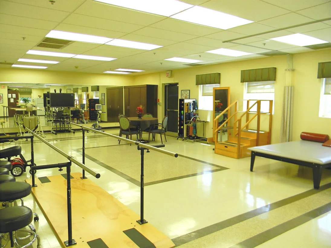A physical therapy rehabilitation room equipped with parallel bars and various exercise equipment.