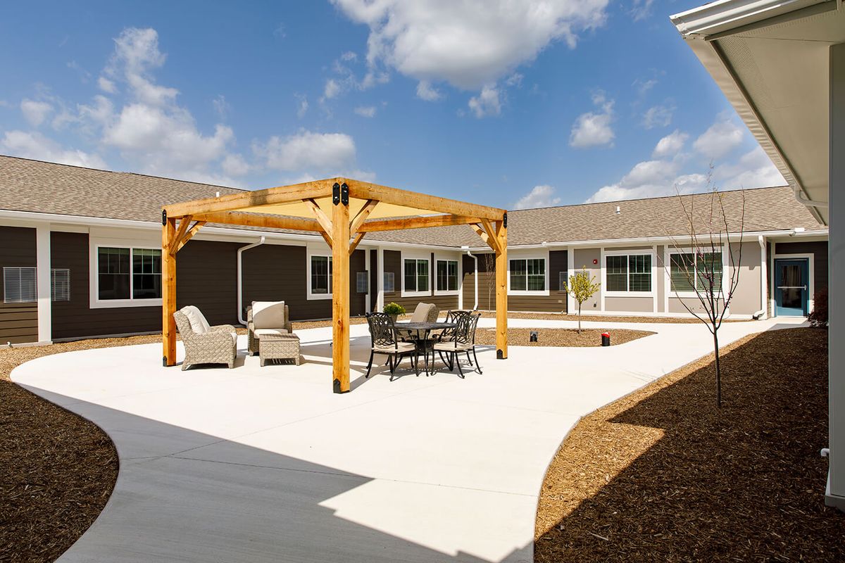 A sunny courtyard features a pergola with outdoor seating and a patio area.