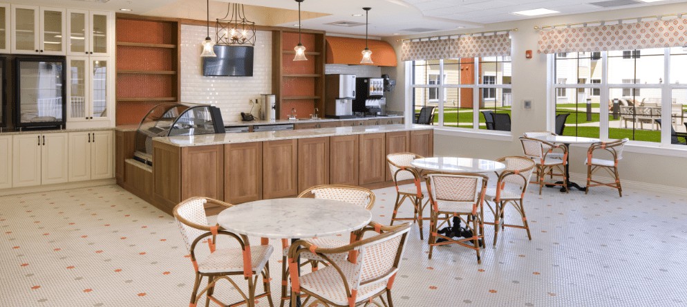 A modern cafe interior featuring round tables and chairs, with a counter area and pendant lighting.
