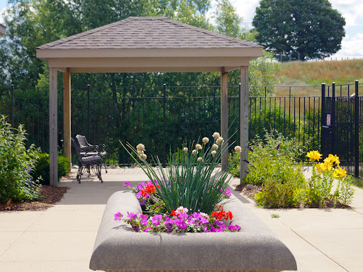 A serene garden area featuring a canopy, vibrant flowers, and a comfortable bench for relaxation.