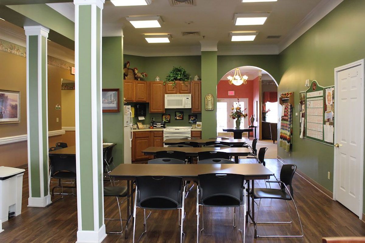 A cozy kitchen and dining area with tables and chairs, featuring a warm color scheme and an archway.