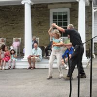 A couple is dancing in front of an audience seated on a porch.