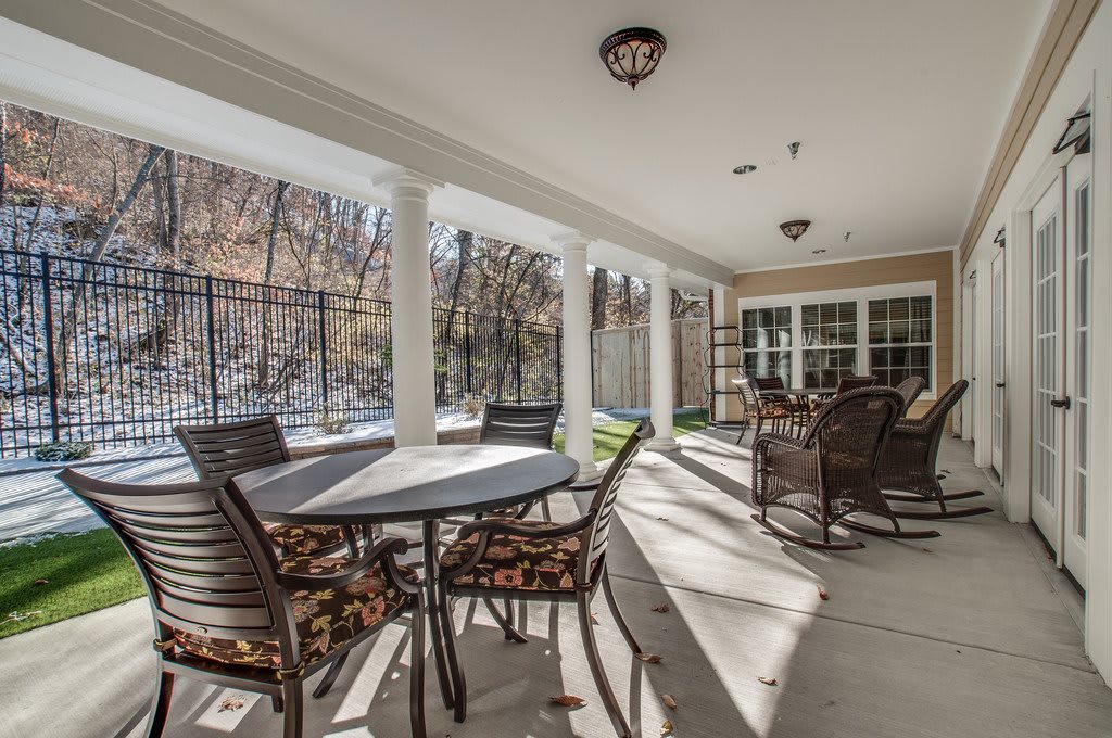 A covered patio with various tables and chairs, providing a cozy outdoor seating area bathed in sunlight.