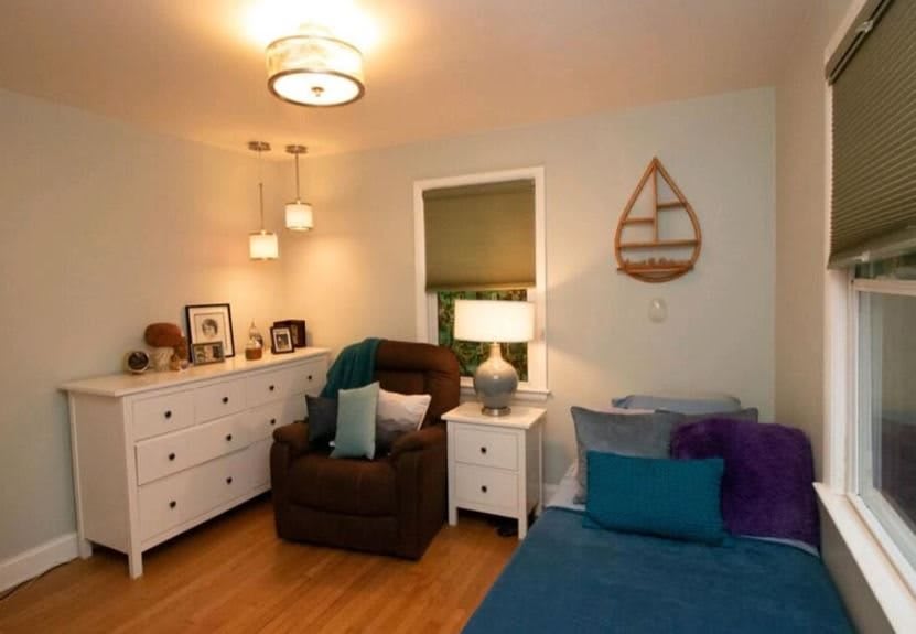 A cozy bedroom with stylish decor, featuring a comfortable armchair and warm lighting.