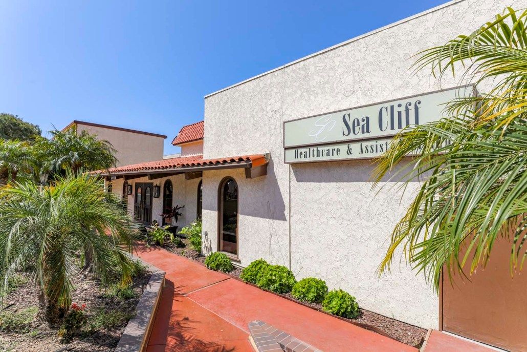 Exterior view of a restaurant with signage and palm trees on a sunny day.