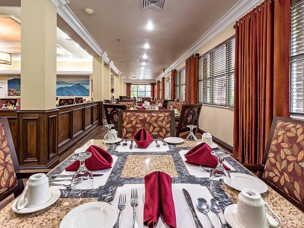 An elegantly set dining table in a spacious restaurant with neatly arranged napkins and cutlery.
