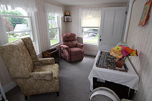 A cozy living room with multiple chairs and large windows letting in natural light.