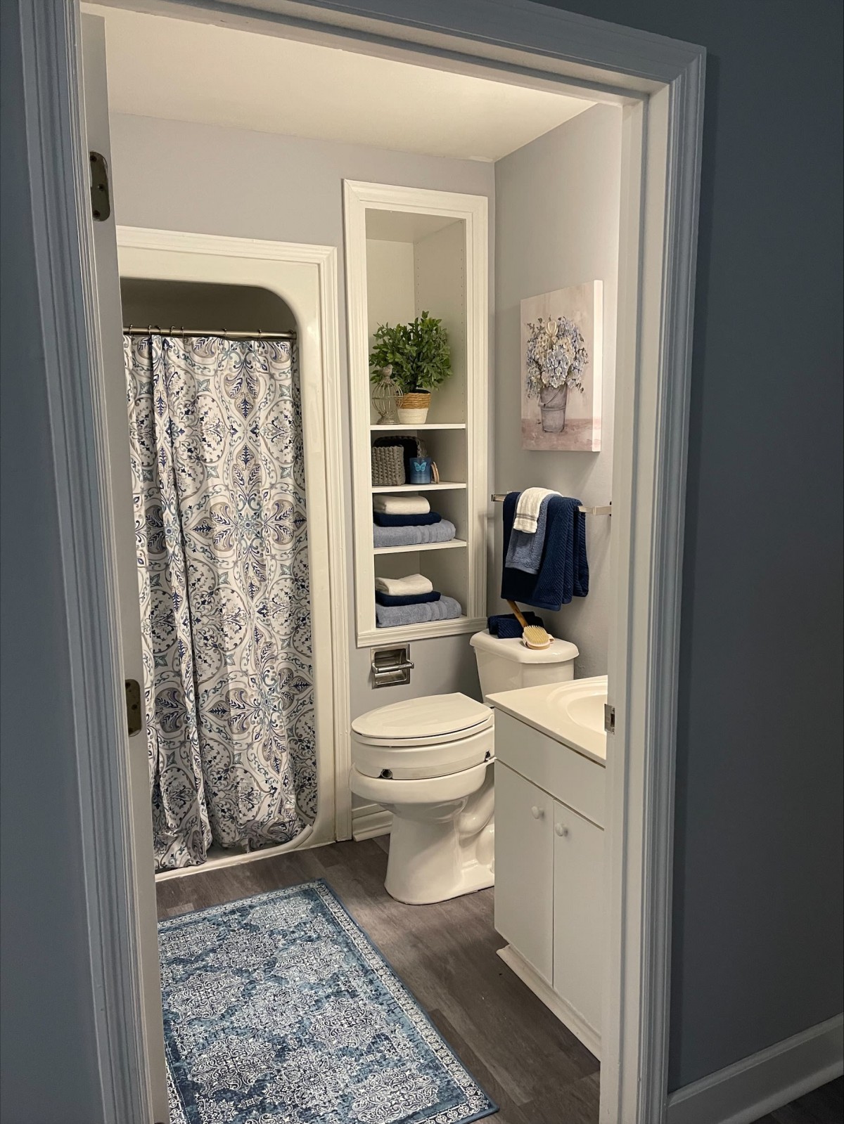 A neatly organized bathroom with a shower curtain, towels, and decorative elements.