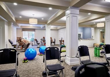 A well-equipped gym area with exercise machines, chairs, and fitness balls.