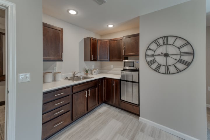 A modern kitchen with dark wood cabinets and a wall clock.