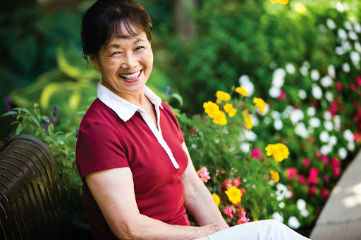 A joyful woman enjoying a sunny day among vibrant flowers.