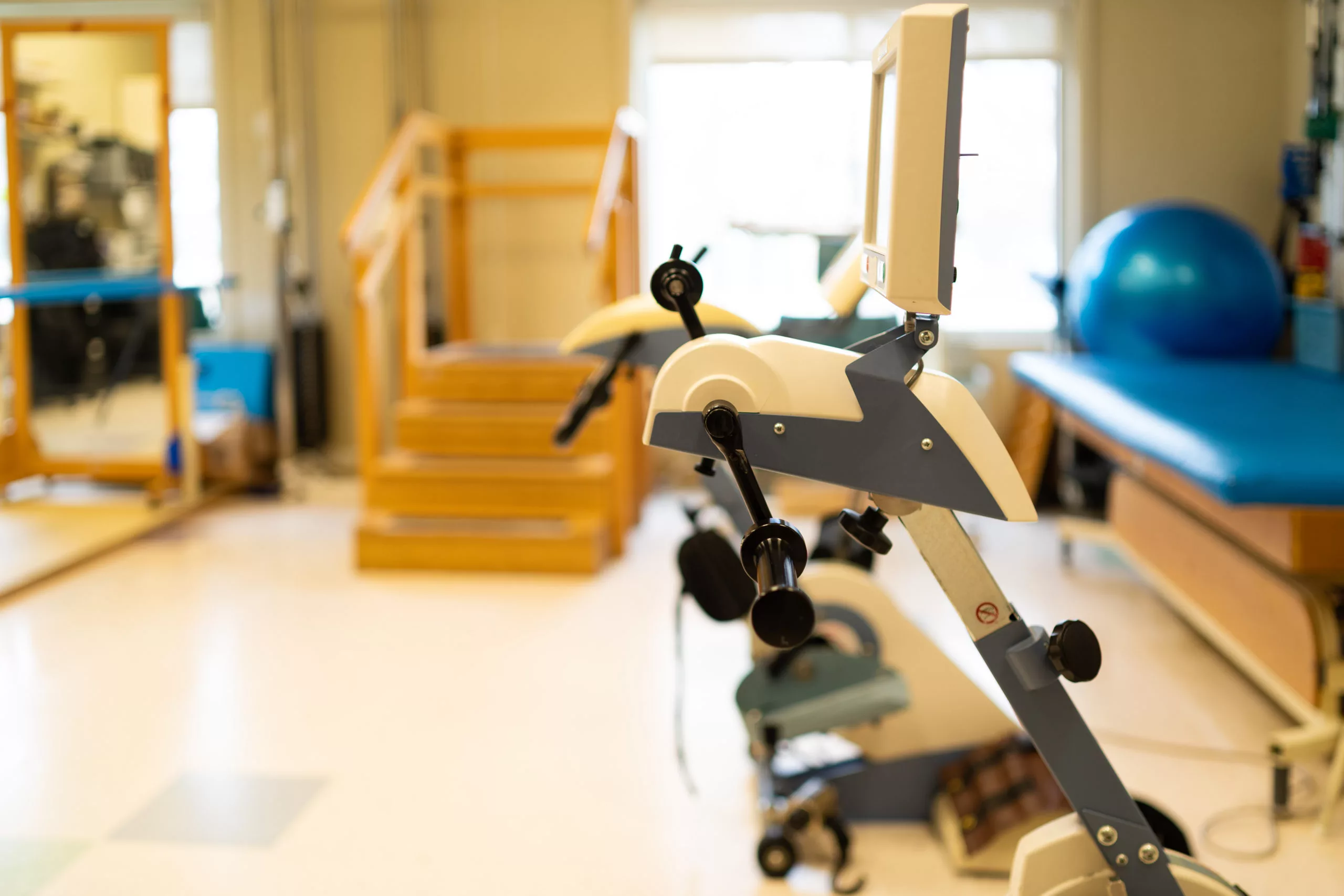 A physical therapy gym featuring exercise equipment and a staircase for rehabilitation exercises.