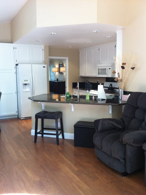 A cozy open-concept kitchen and living area featuring a recliner and bar stools at a counter.