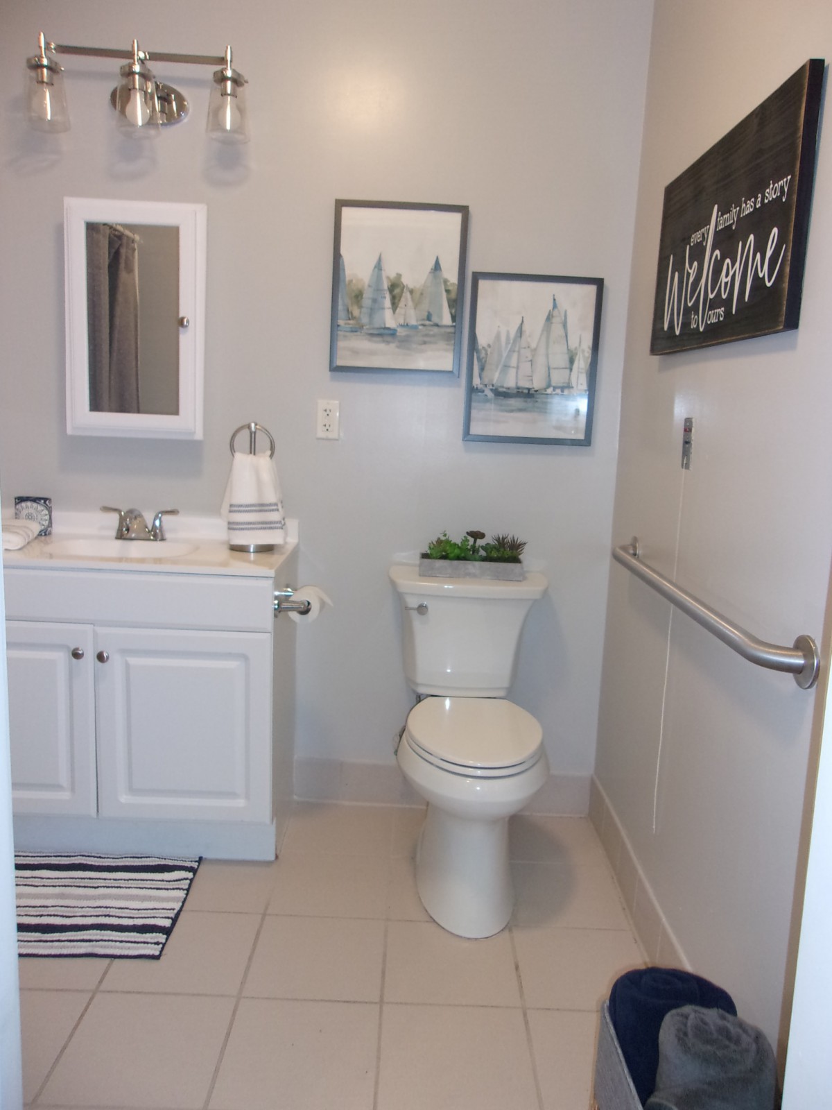 A modern bathroom with a white vanity, toilet, mirror, and decorative wall art.