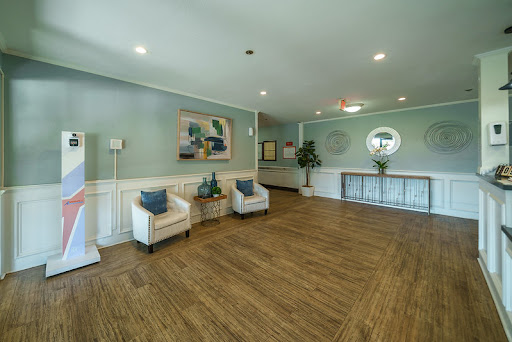 A spacious and modern lobby featuring light-colored walls, wooden flooring, and contemporary furniture.