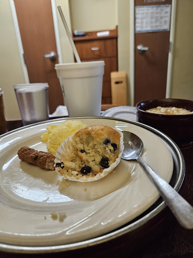 A cozy breakfast spread featuring a muffin with blueberries, sausage, and a cup of coffee.