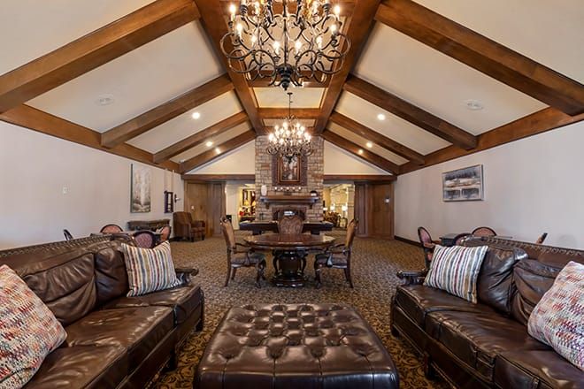 A luxurious and cozy living room with wood beams and chandeliers.