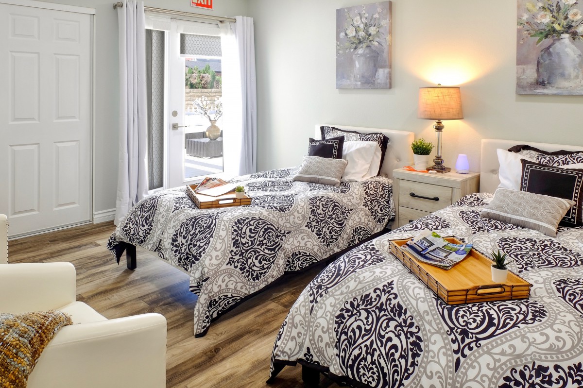 A modern and cozy bedroom with two neatly made beds, a nightstand, and elegant decor.