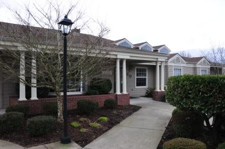 A residential house with a pathway leading to the entrance, surrounded by landscaped bushes.