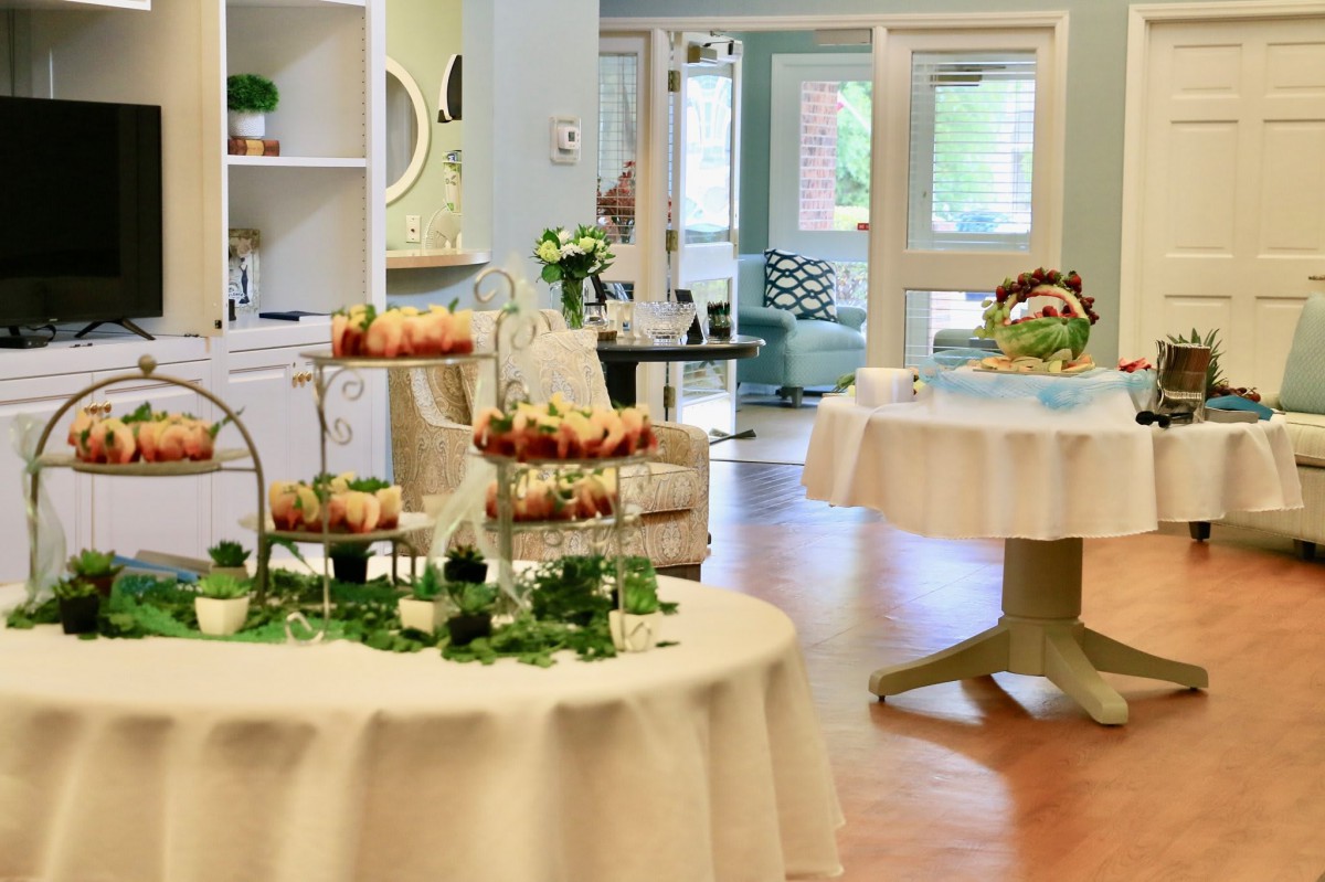 A beautifully decorated reception area with tables set up for an event, displaying a variety of food items.
