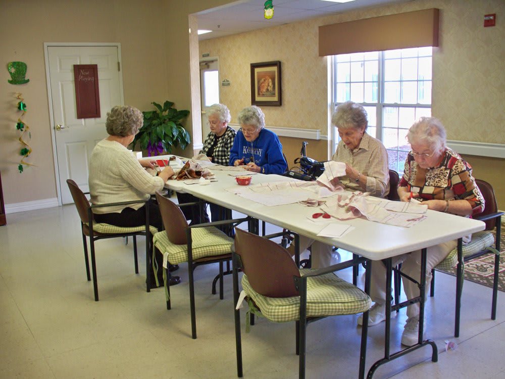 A group of seniors engaged in an activity around a table indoors.