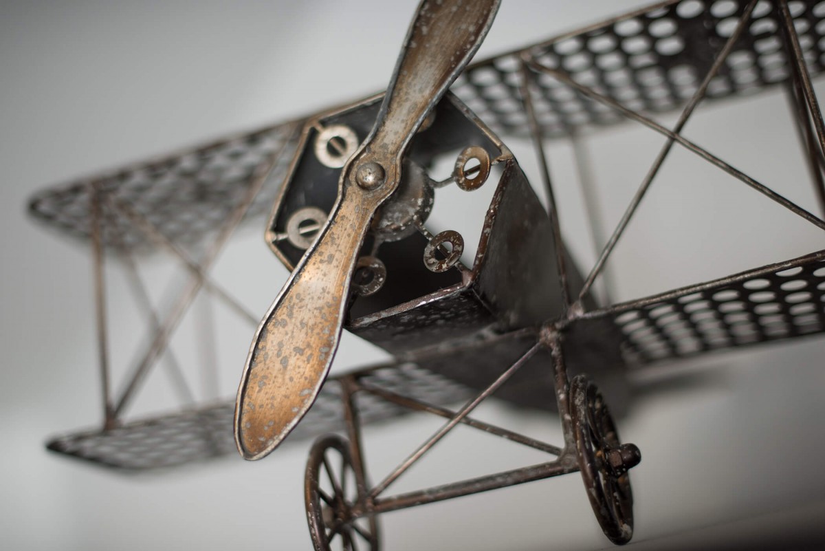 A vintage metal model airplane showcasing a detailed propeller and wheels.