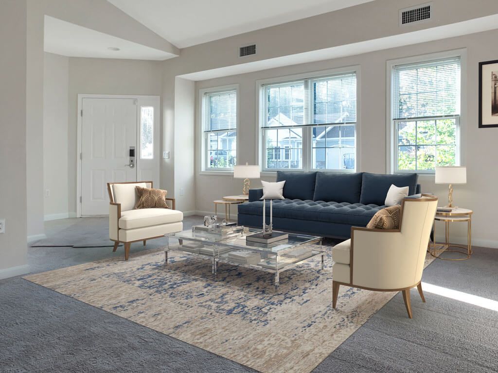 A modern living room with a blue sofa and cream chairs around a glass coffee table.