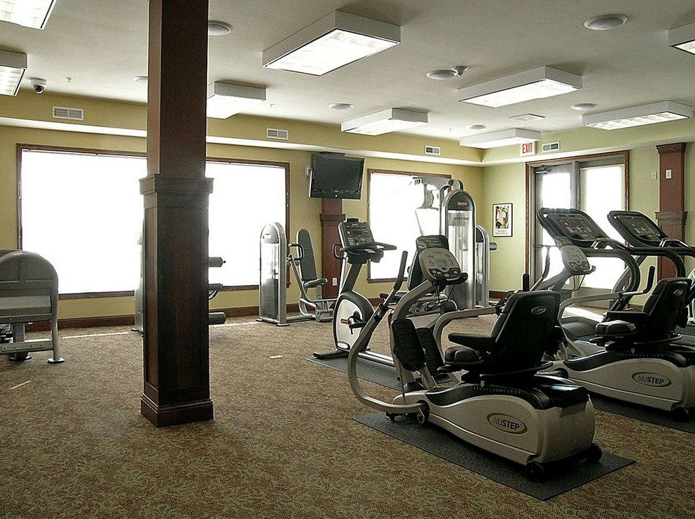 A well-lit gym with various exercise equipment including treadmills and stationary bikes.