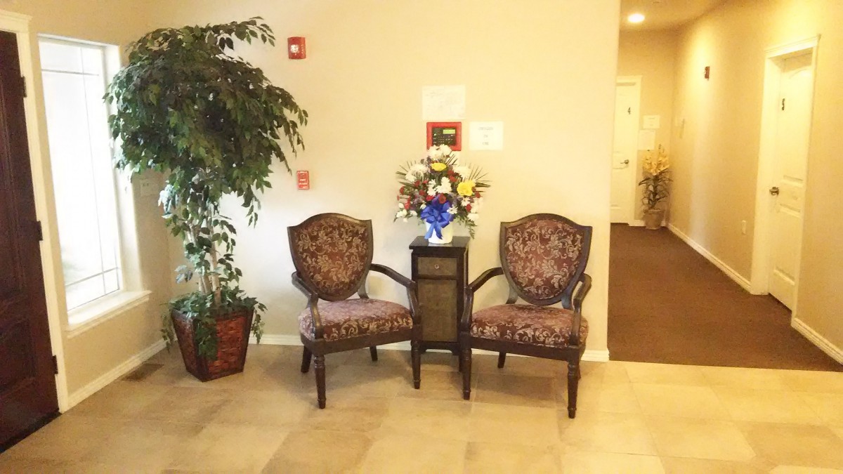 Two ornate chairs with a floral arrangement between them in a warmly lit lobby.