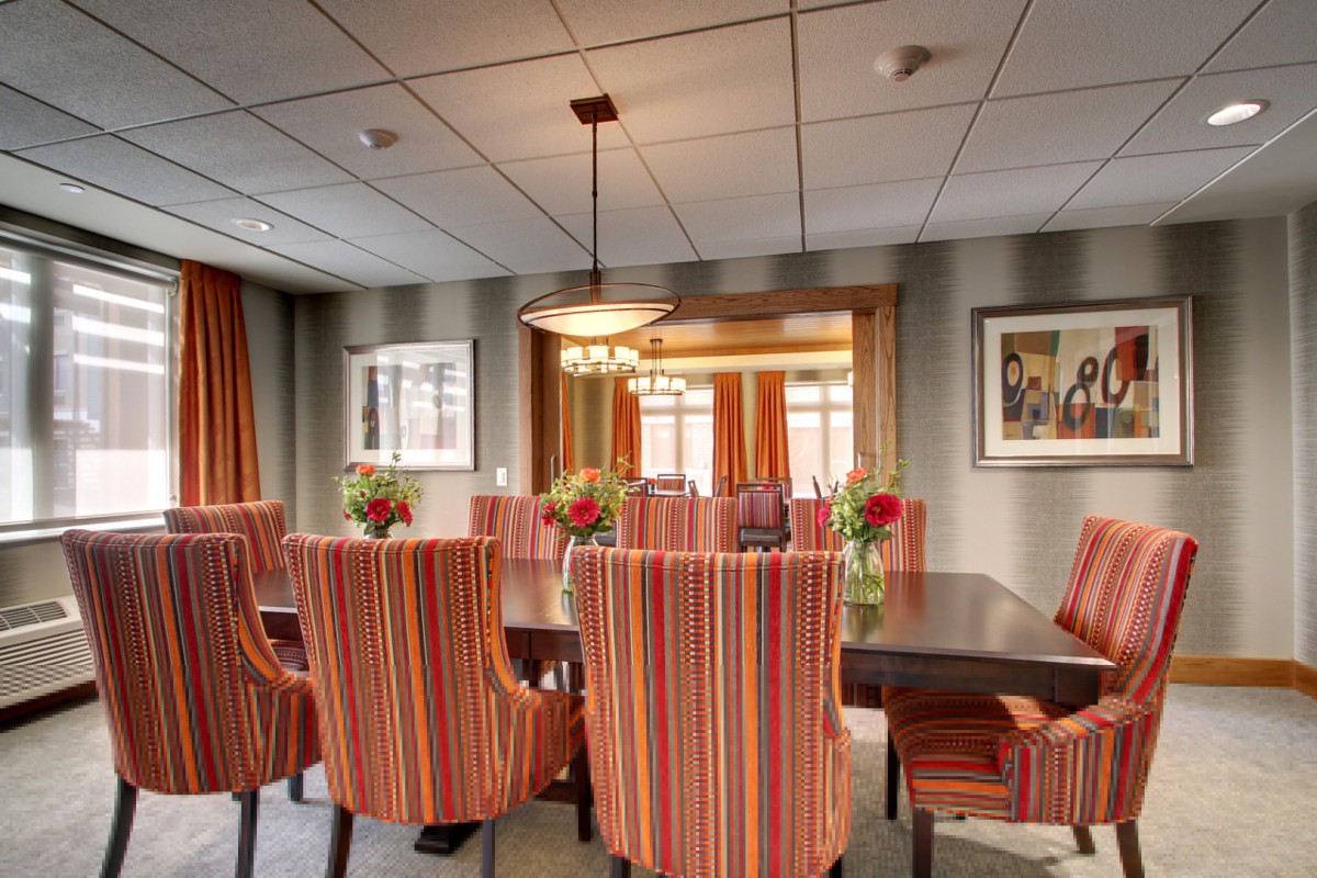 A modern dining room with striped chairs and a central chandelier.