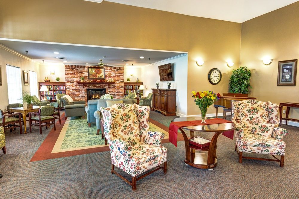 A cozy living room with floral armchairs, a fireplace, and warm decor.