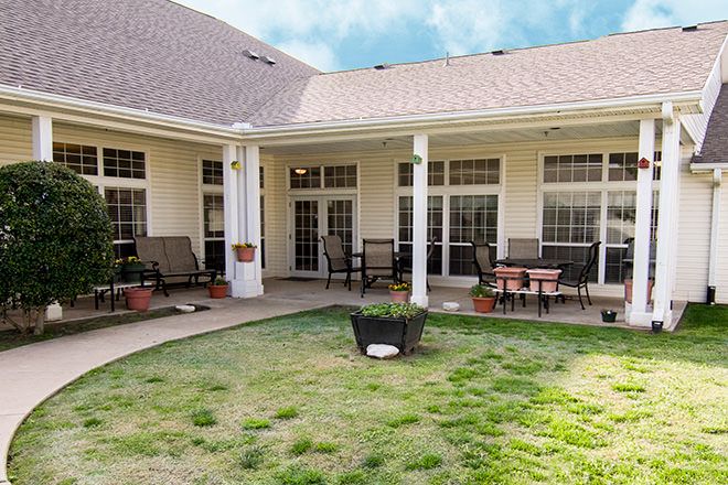 A cozy patio area with outdoor furniture and a small lawn, surrounded by a building's exterior.